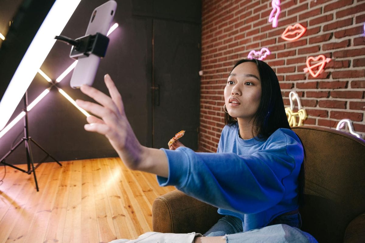 Asian woman creates live stream content in stylish neon lit room.