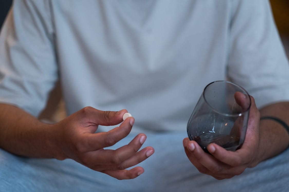 Free Person Taking a Pill and Holding Glass Stock Photo