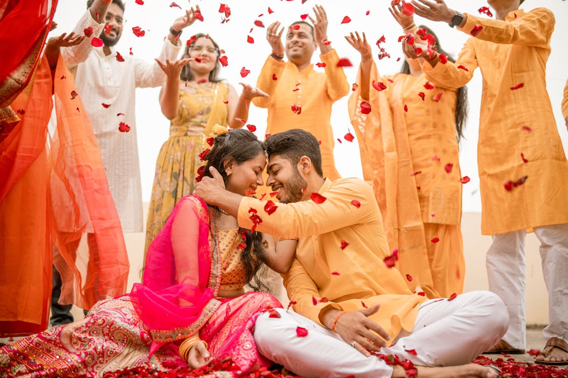 Free Happy moment at an Indian wedding with petals raining over a smiling couple and friends. Stock Photo