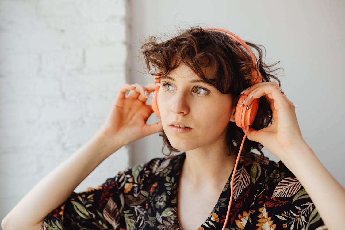 Woman wearing headphones listening to music — representing trending sounds used in faceless short videos.