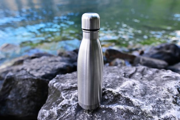 Closeup of steel eco thermo water bottle on the surface of the lake in the mountains