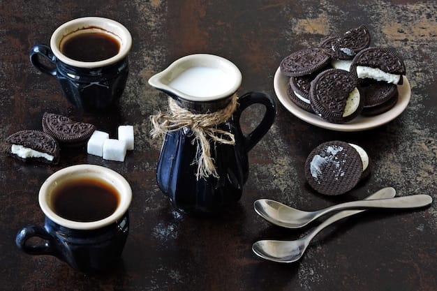 Two cups of espresso, a jug of milk and chocolate chip cookies with a white filling.