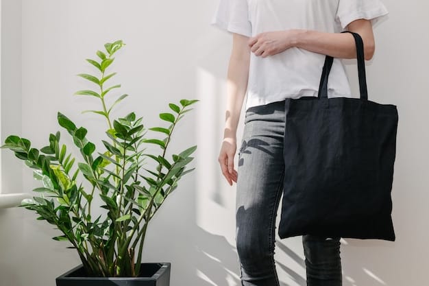 Young woman holding black textile eco bag against white wall.