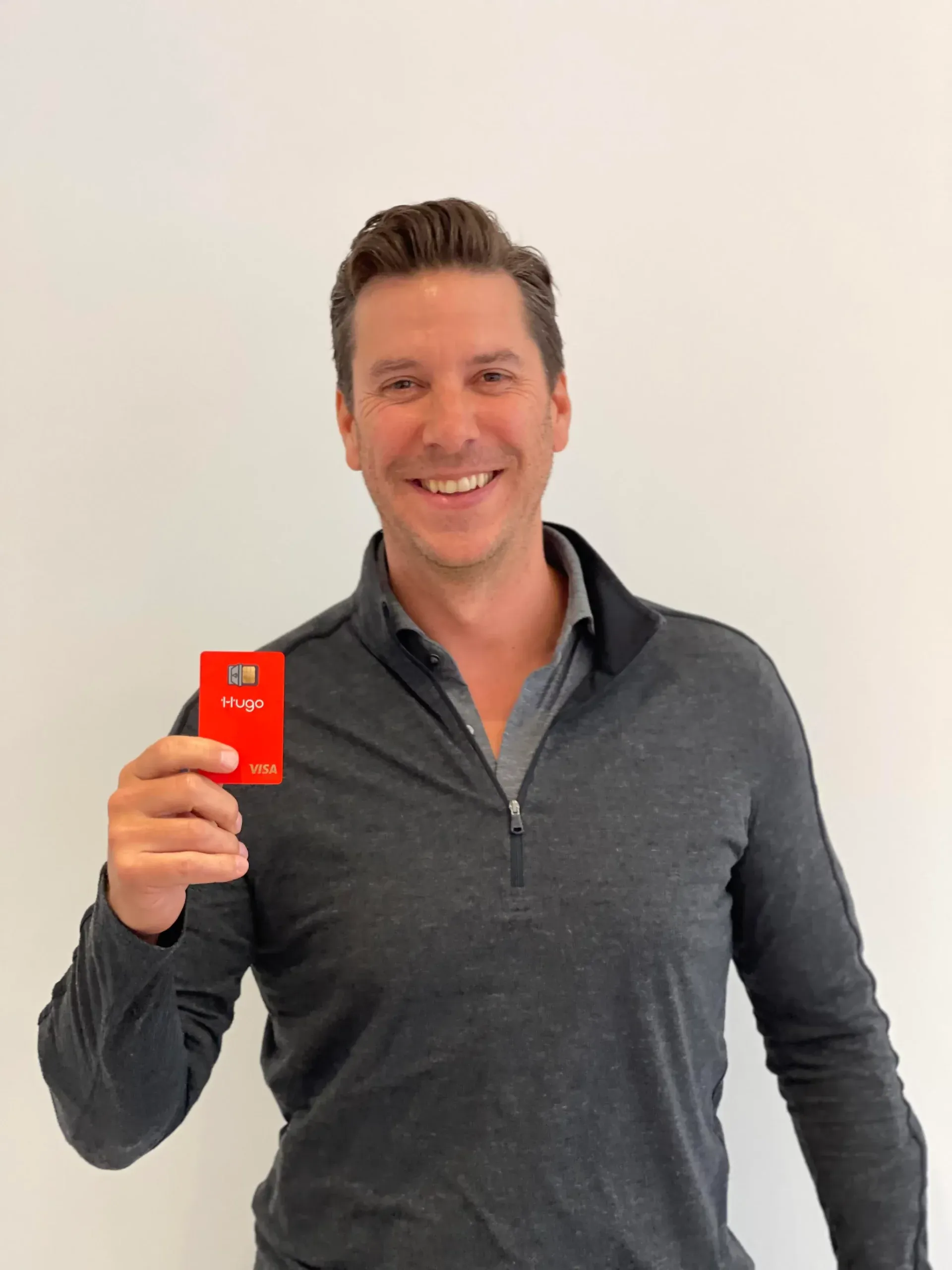 Man smiling holding red credit card.