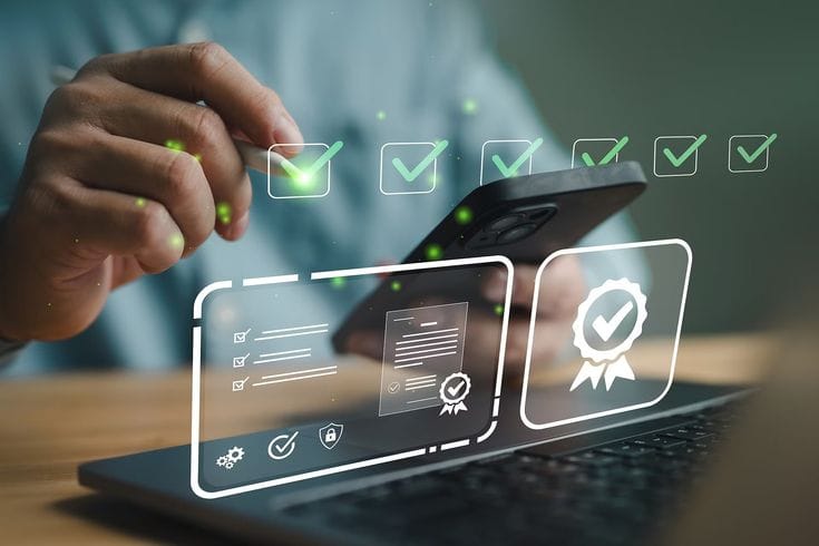 This may contain: a person holding a cell phone in front of a laptop with icons coming out of it