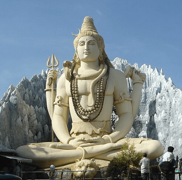 A photo of a huge white statue of a 4-armed Lord Shiva sitting in Padmasana, holding a trident and drum in His upper hands..