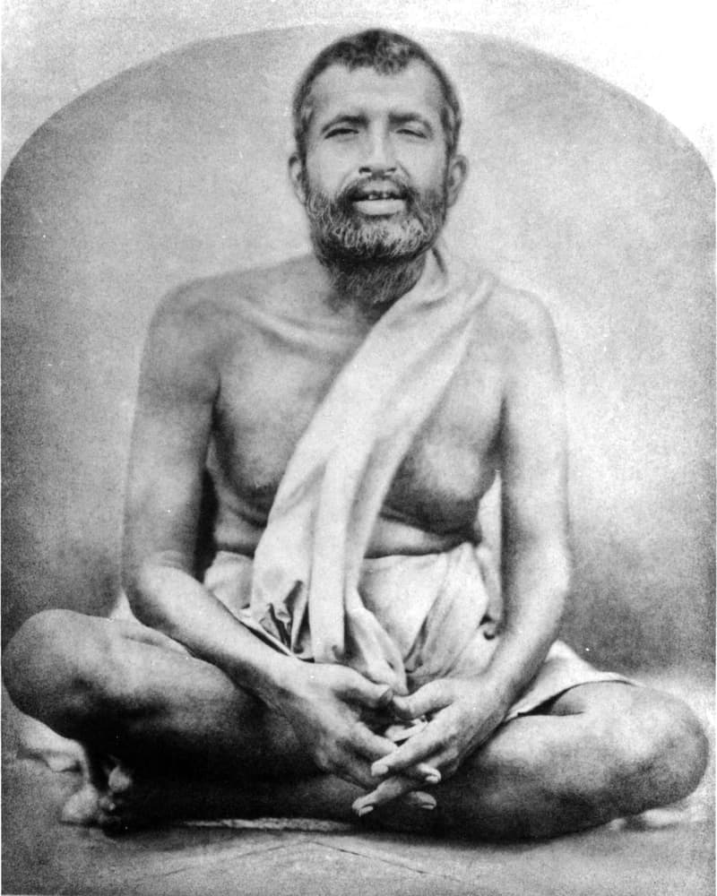 A real black-and-white photo of Swami Ramakrishna Paramahamsa sitting cross-legged.