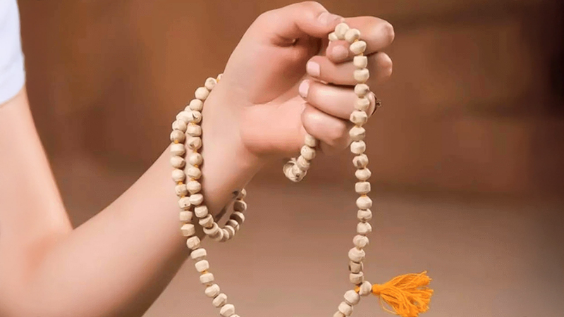 A photo of a hand holding a Hindu Jap Mala.