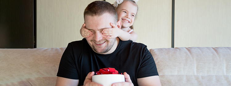 Little girl giving a surprise gift to her dad on father's day