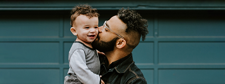 Man holding and kissing a baby