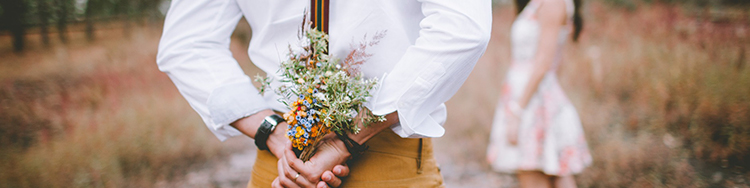 Man hiding flowers behind to give a surprise