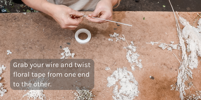 Two hands grabbing a wire and twisting floral tape around it