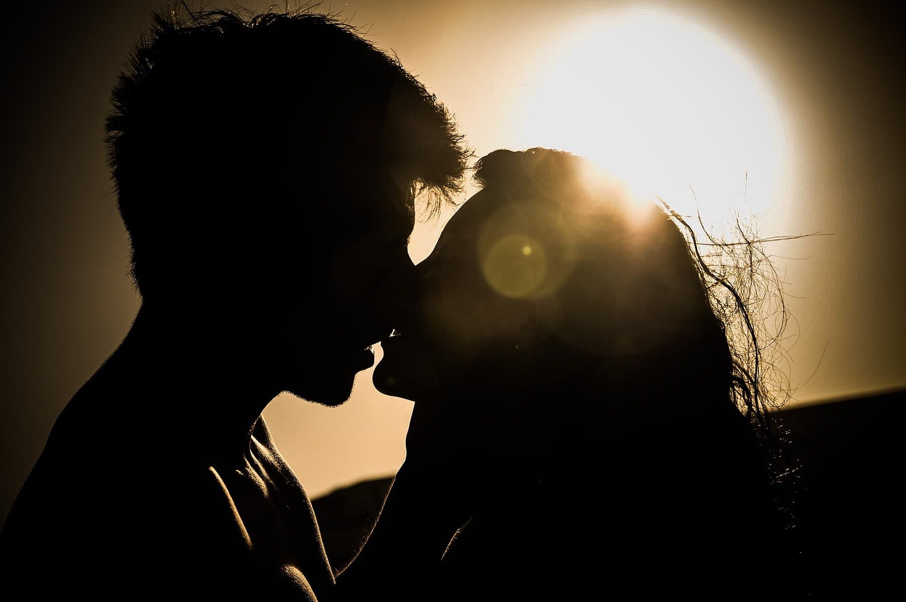 Silhouette of a couple kissing at sunset