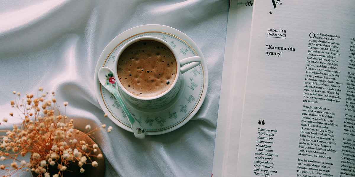 Table decorated with dried flowers and lemons along with a ceramic mug with Coffee in it. 