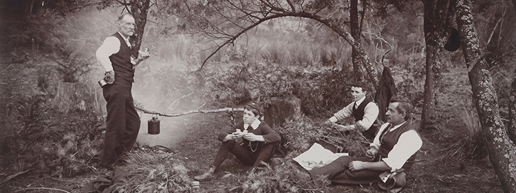 Four men sitting on ground during the event of collecting Wattle