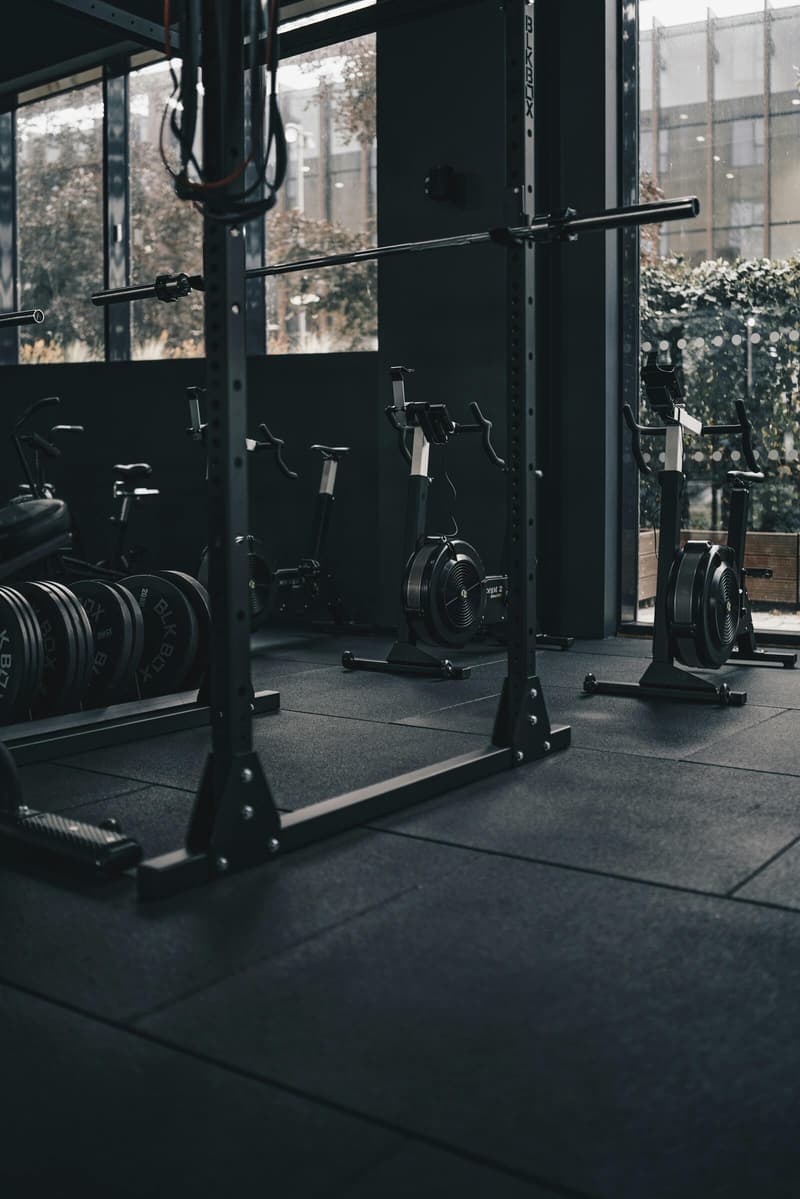 Dark gym with squat rack, weight plates and air bikes
