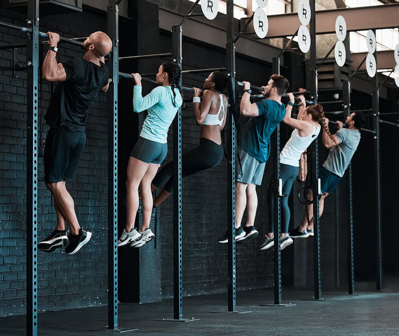 Group of people laughing and high-fiving during a group fitness class in a bright gym