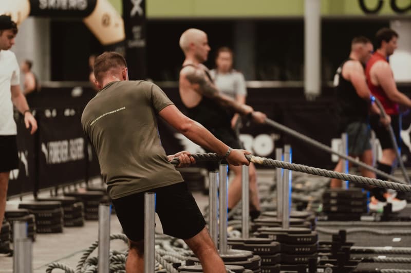 People exercising with battle ropes in a gym.
