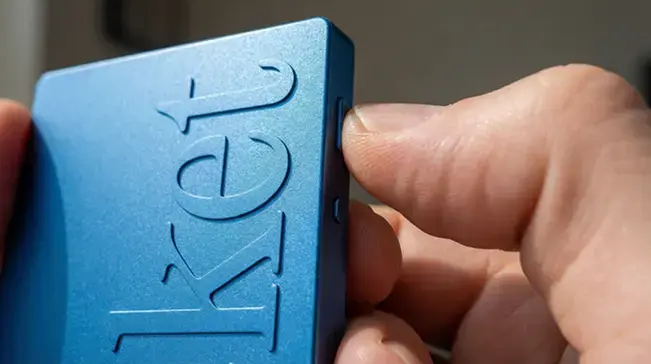 A thumb pressing the single side button on a blue Pocket device